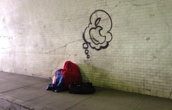 Homeless person sleeps under graffiti thought bubble of Apple, Inc. logo in 2nd St. tunnel in Los Angeles